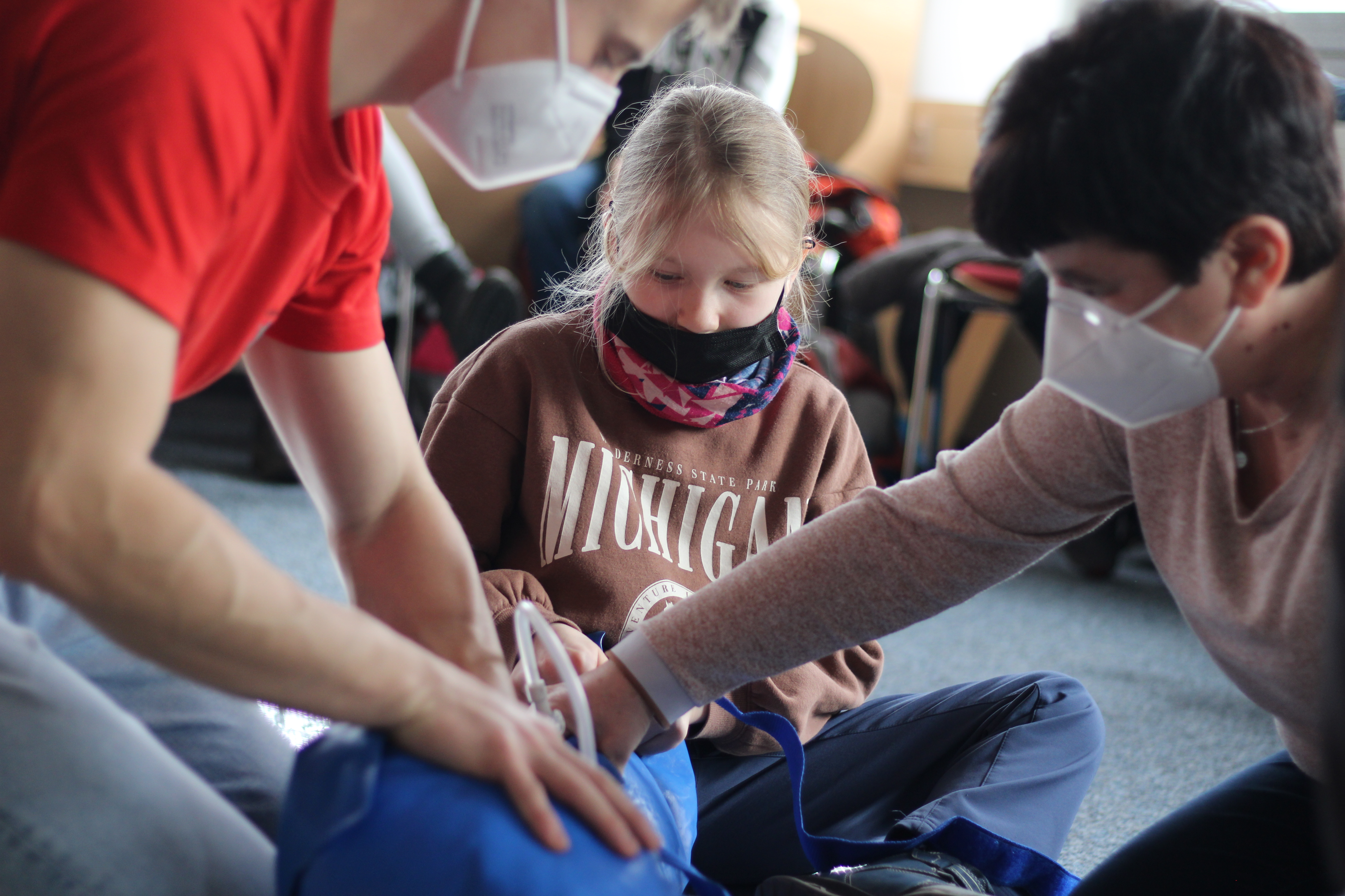 KI generiert: Das Bild zeigt eine Gruppe von Menschen, die an einer Erste-Hilfe-Übung mit einer Puppe teilnehmen. Sie tragen Masken und konzentrieren sich auf die Durchführung der Übung.
