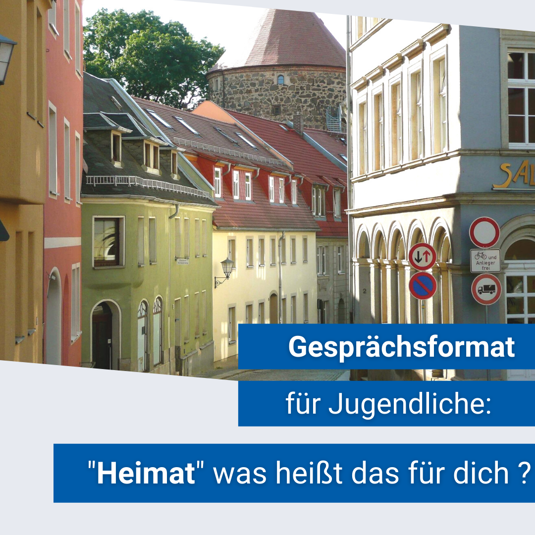 KI generiert: Das Bild zeigt eine malerische Altstadtstraße mit bunten Gebäuden und einem runden Turm im Hintergrund. Der Text weist auf ein Gesprächsformat für Jugendliche zum Thema "Heimat" hin.